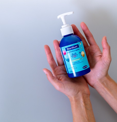Two hands presenting a bottle of Sterillium apothekenseife with light grey background.