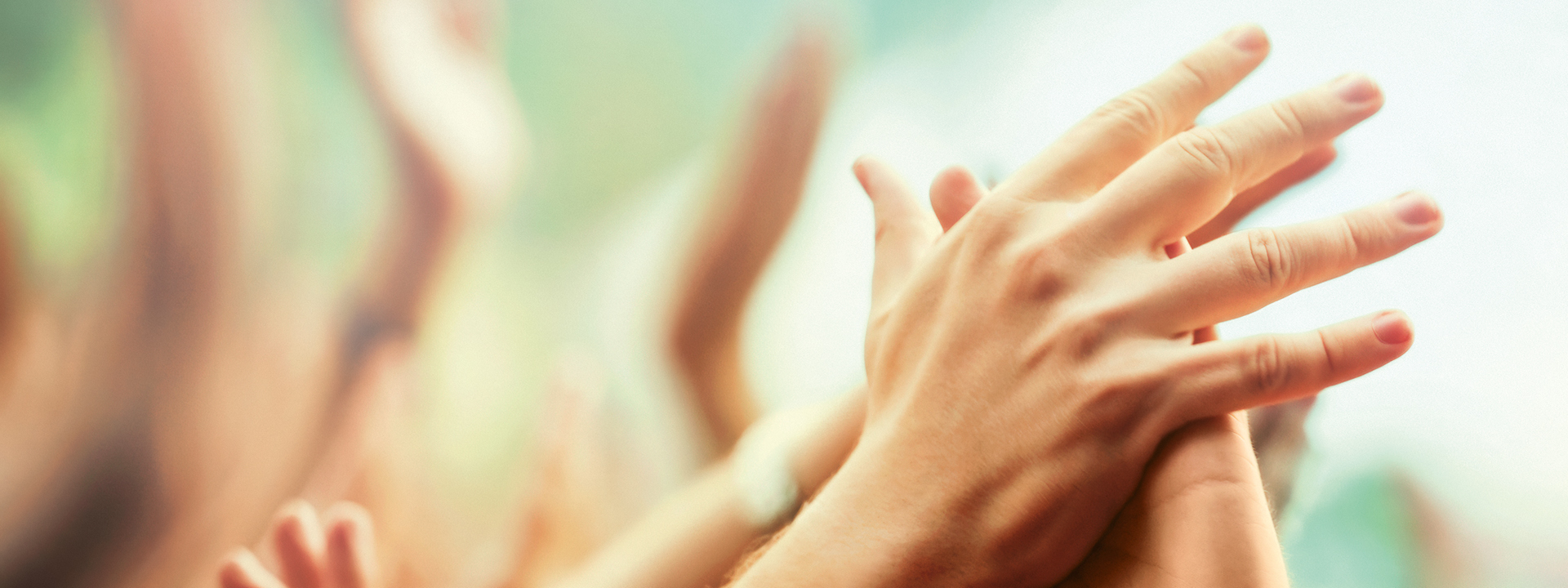 Two hands touching. Other hands in the background.