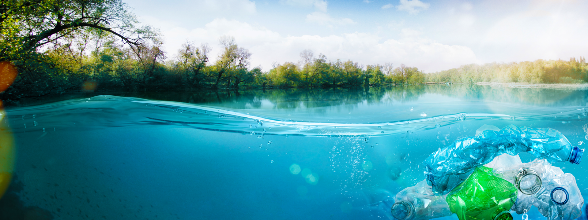 Blue lake water with plastic bottles in it and trees in the background.