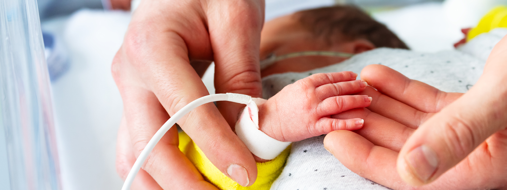 Two hands touching the hand of a baby