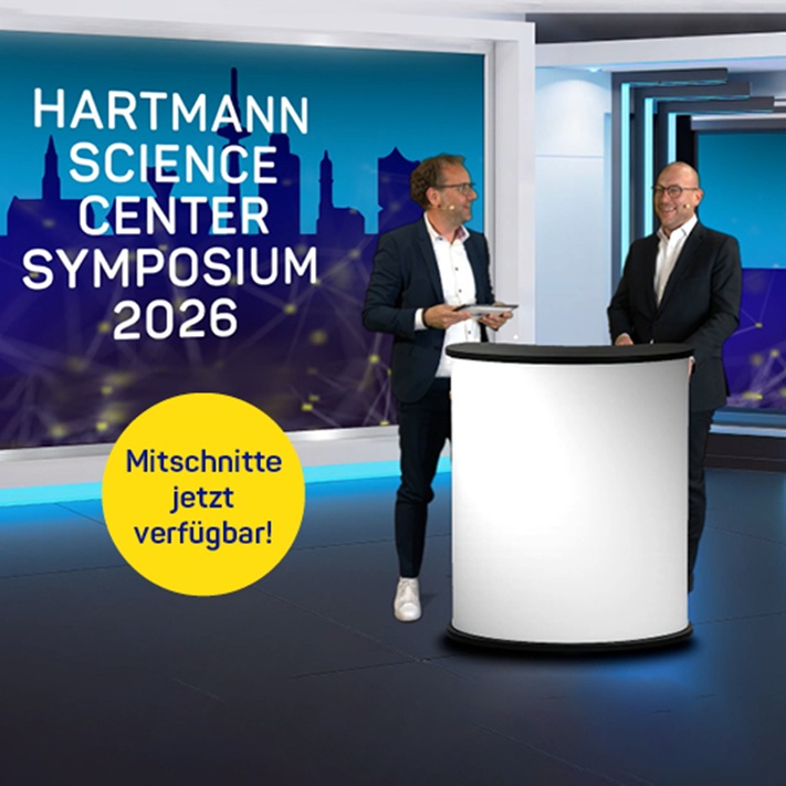 Zwei Referenten mit Mikrofon hinter einem Rednerpult mit dem Text „HARTMANN SCIENCE CENTER Symposium 2026“